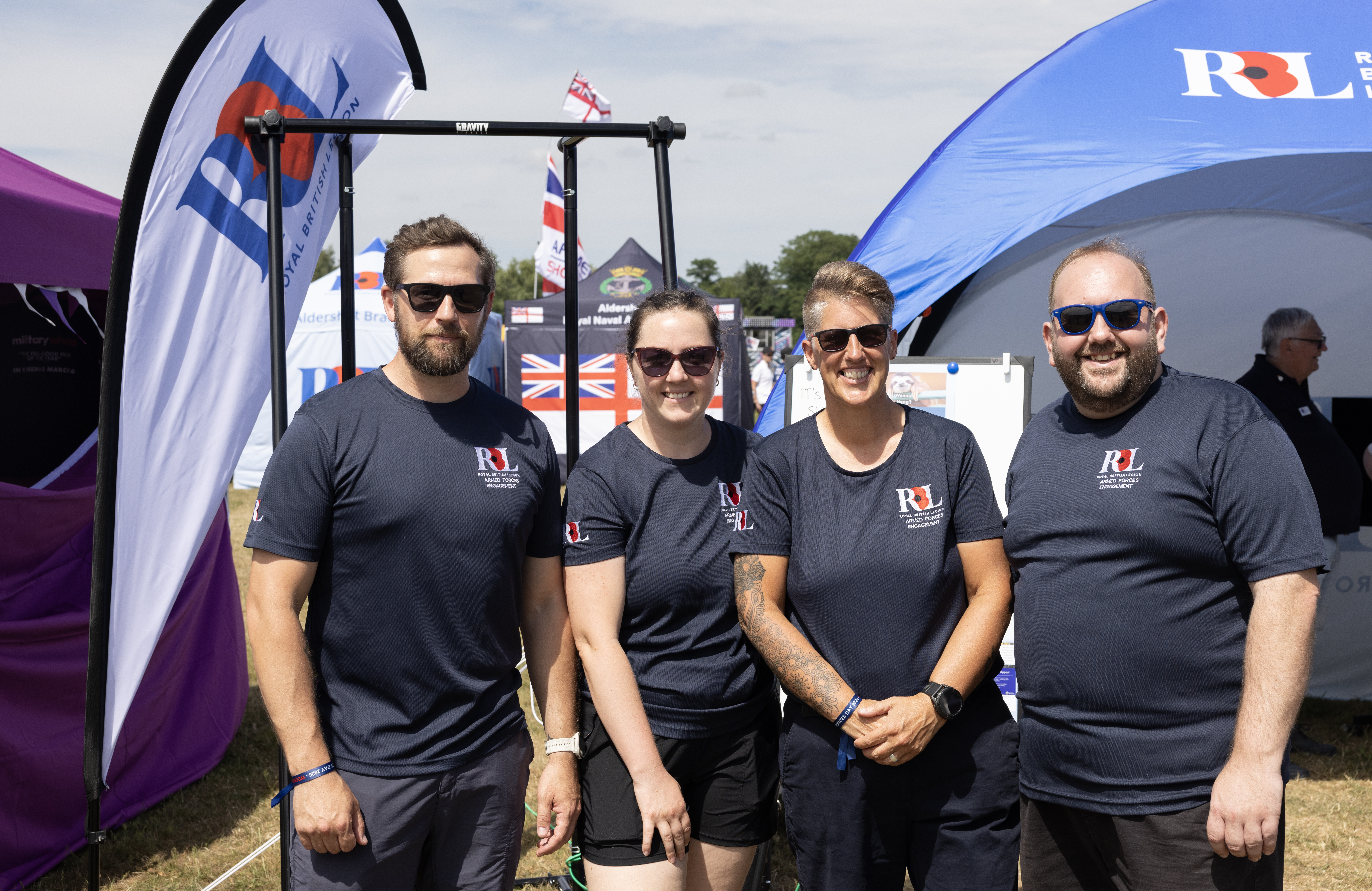 Four serving military members standing together at a Royal British Legion Armed Forces Day event.